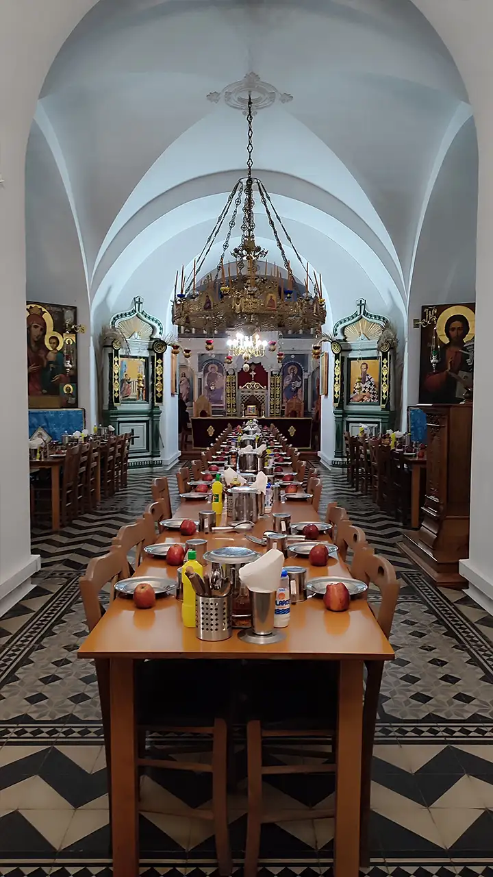 Трапезная Андреевского скита на Афоне: длинные столы, иконы и алтарь в конце зала