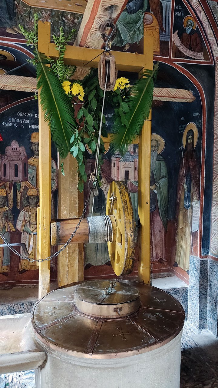 Святой источник архангелов в монастыре Дохиар на Афоне, украшенный зеленью и цветами у росписей храма